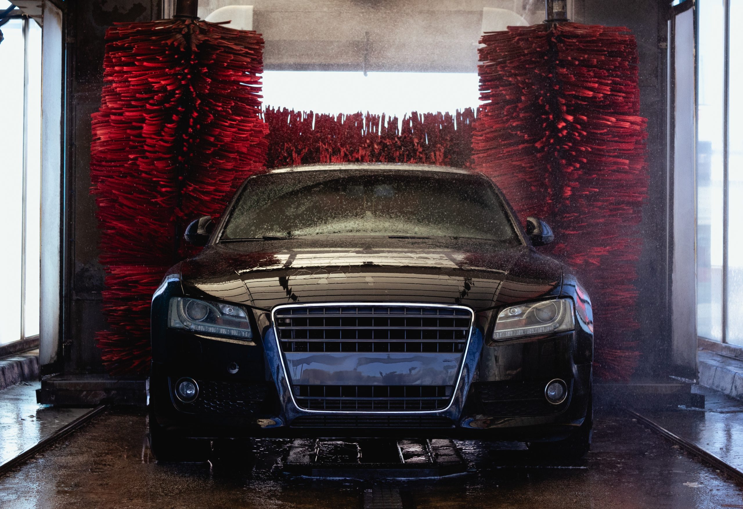 The,Black,Car,Is,On,An,Automatic,Car,Wash,And A black car driving through a car wash
