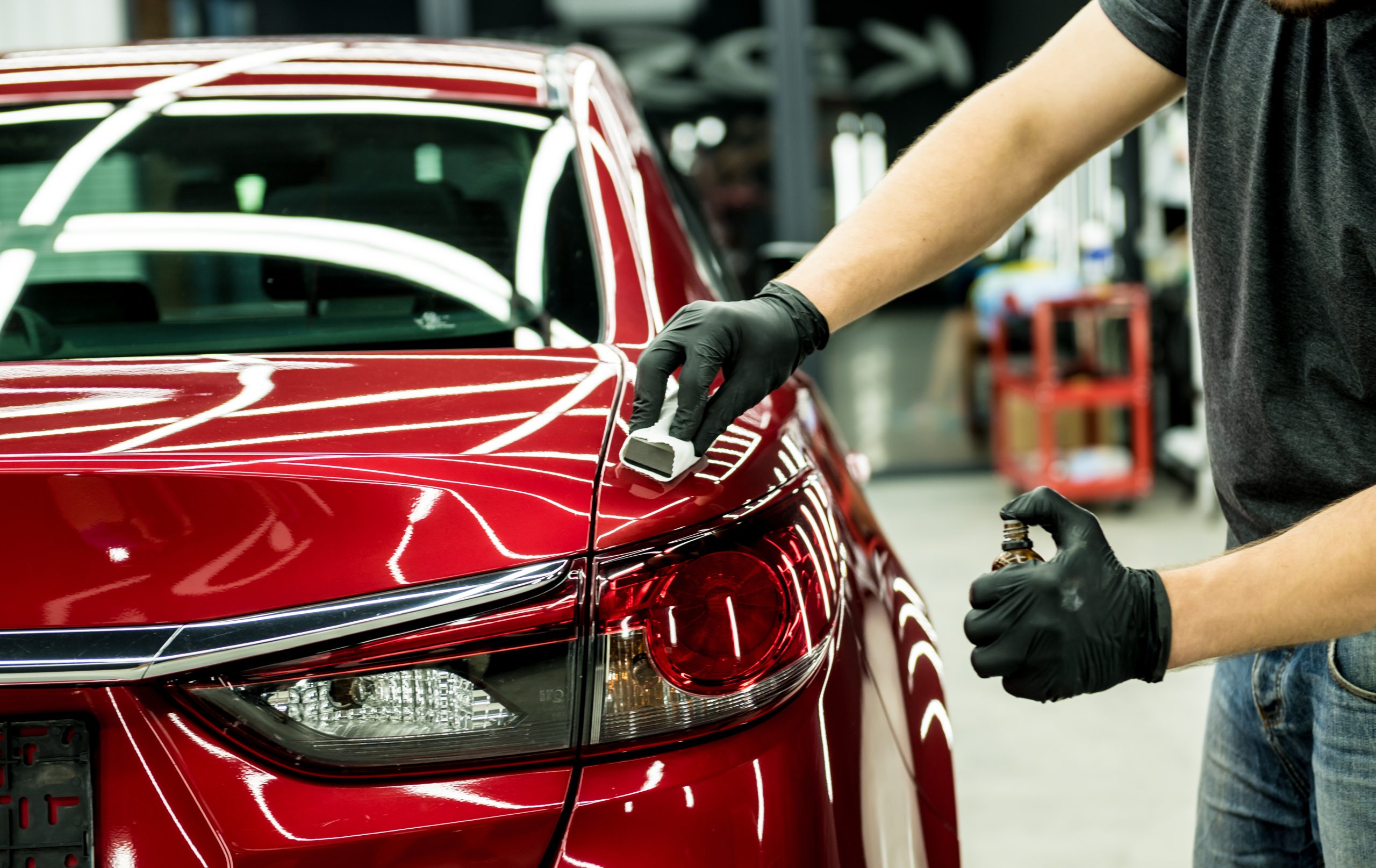 Car,Service,Worker,Applying,Nano,Coating,On,A,Car,Detail. A technician applying wax to a red car