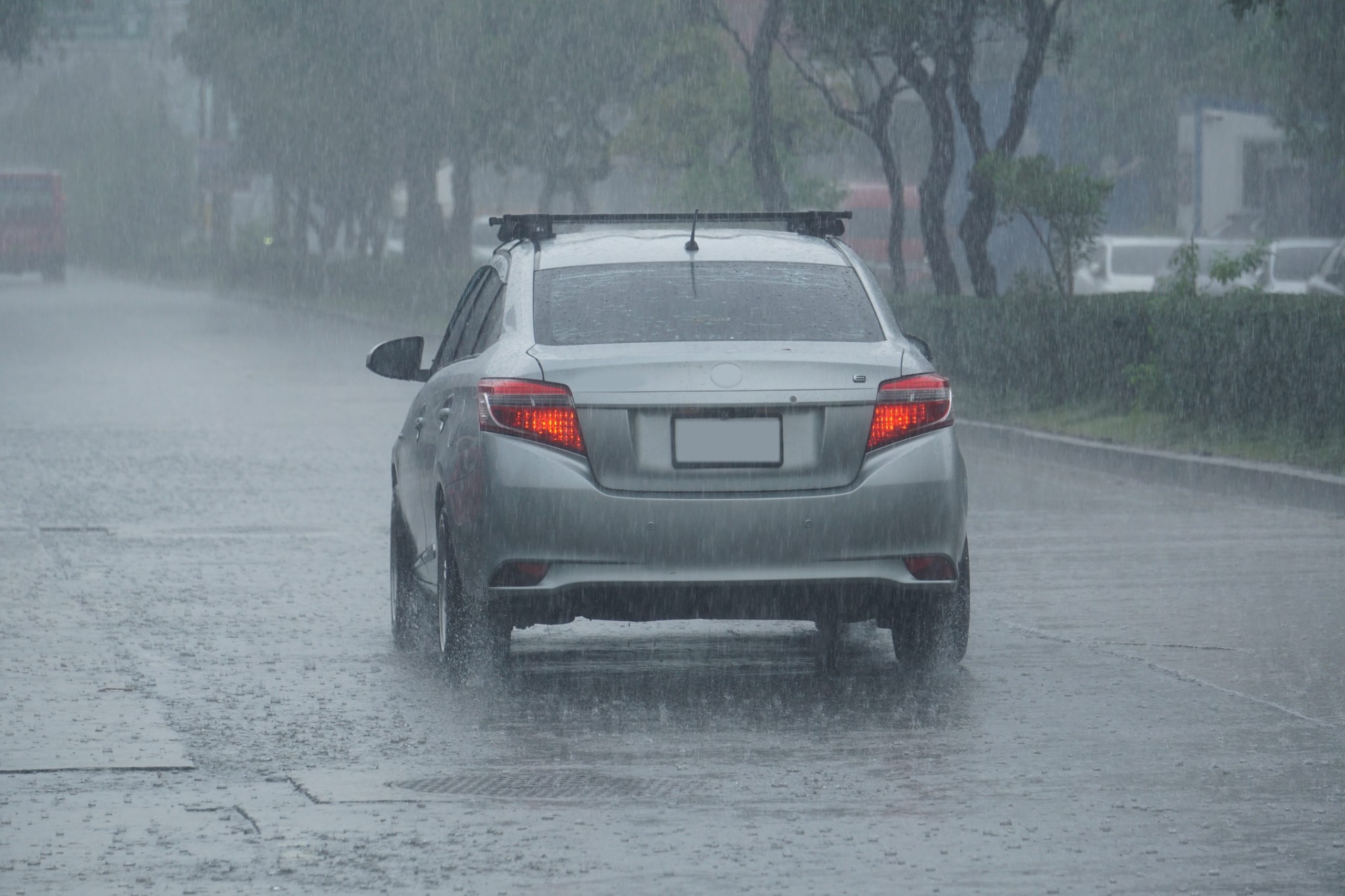 Rain,Water,Drop,Falling,To,The,Floor,In,Heavy,Rain A rear view of a gray car driving through the rain