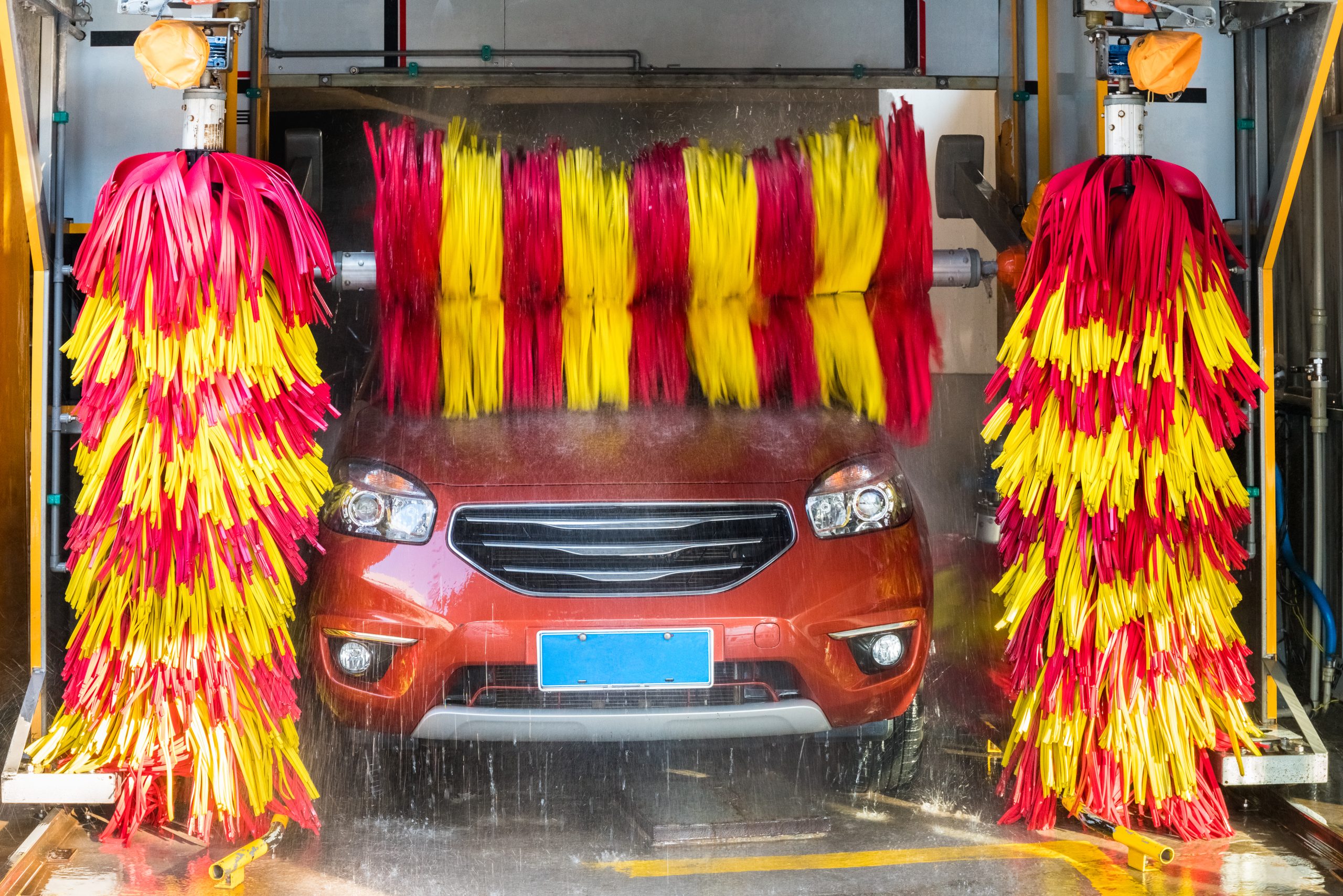 Automatic,Brush,Car,Washing,Closeup An orange SUV going through an automatic car wash with red and yellow brushes
